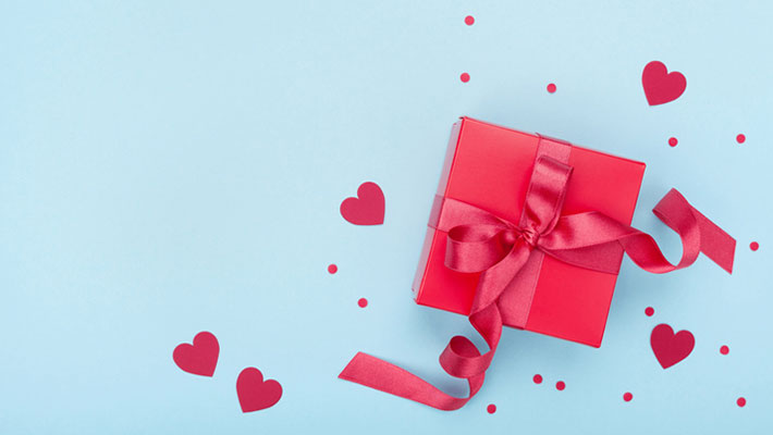 Present or gift box, paper heart and confetti on blue background top view. Valentines day greeting card.