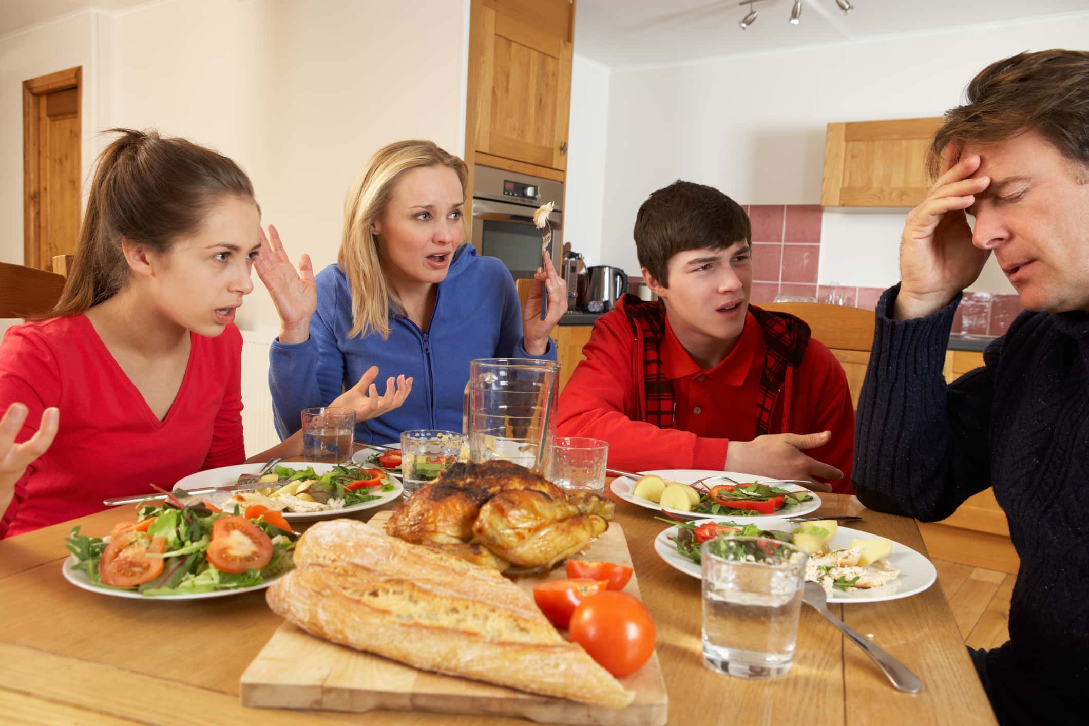 Teenage Family Having Argument Whilst Eating Lunch Together In Kitchen Shouting At Each Other Sitting At Table