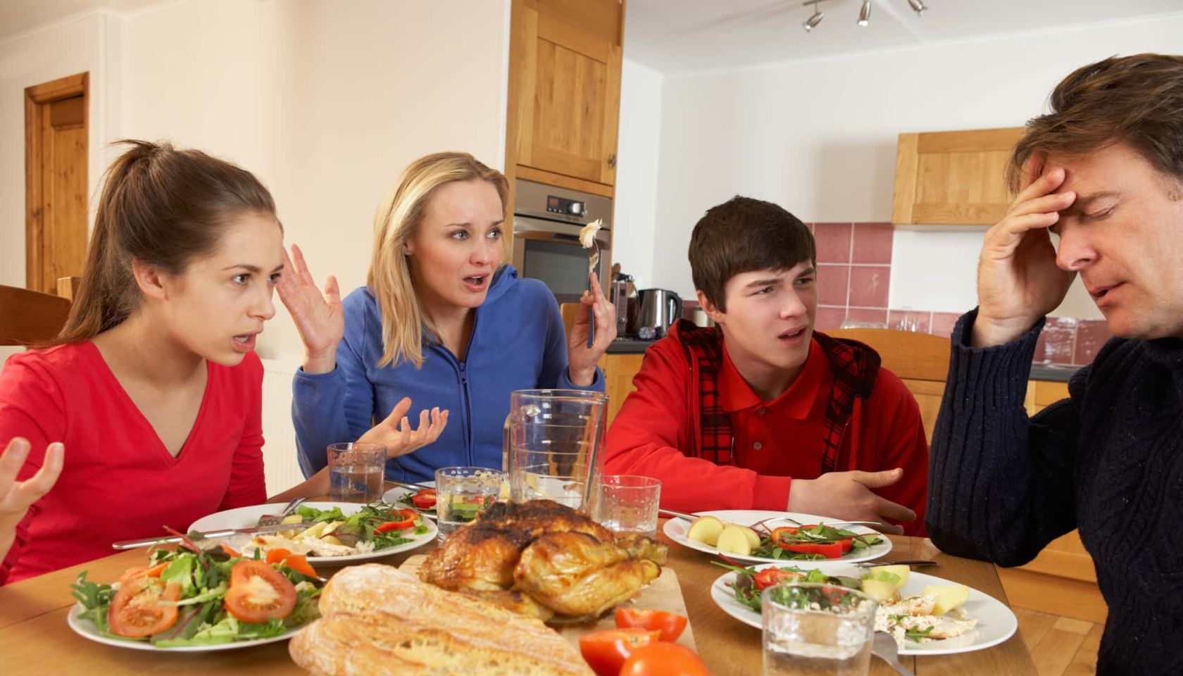 Teenage Family Having Argument Whilst Eating Lunch Together In Kitchen Shouting At Each Other Sitting At Table