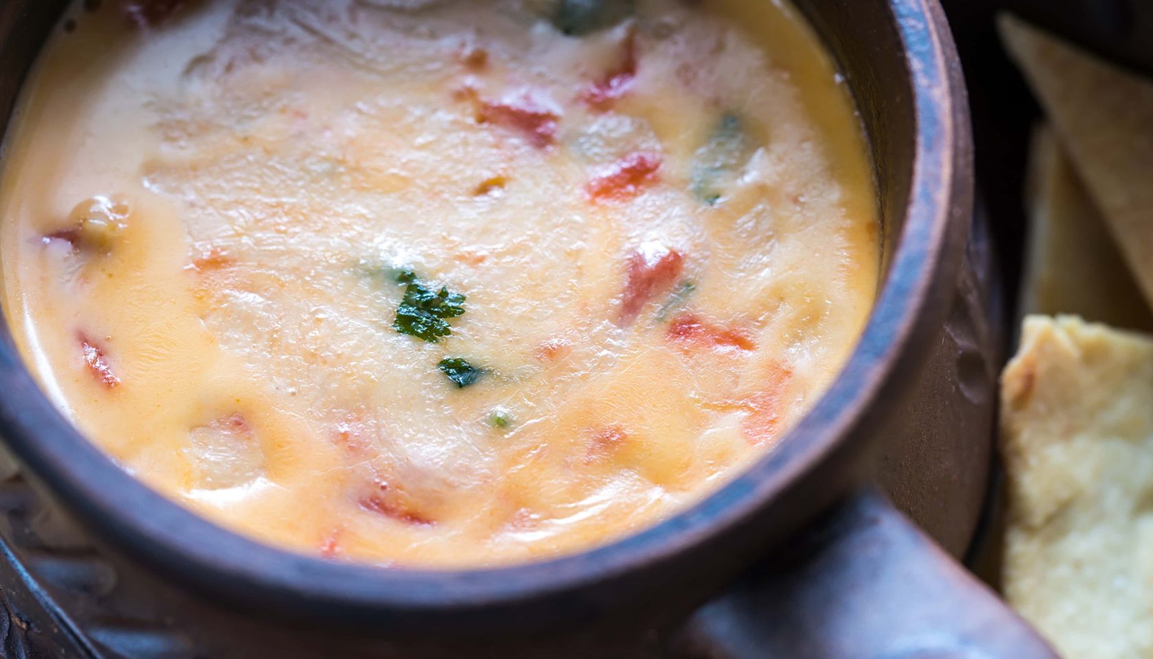 chili con queso in bowl close up with red chilis and iron pot