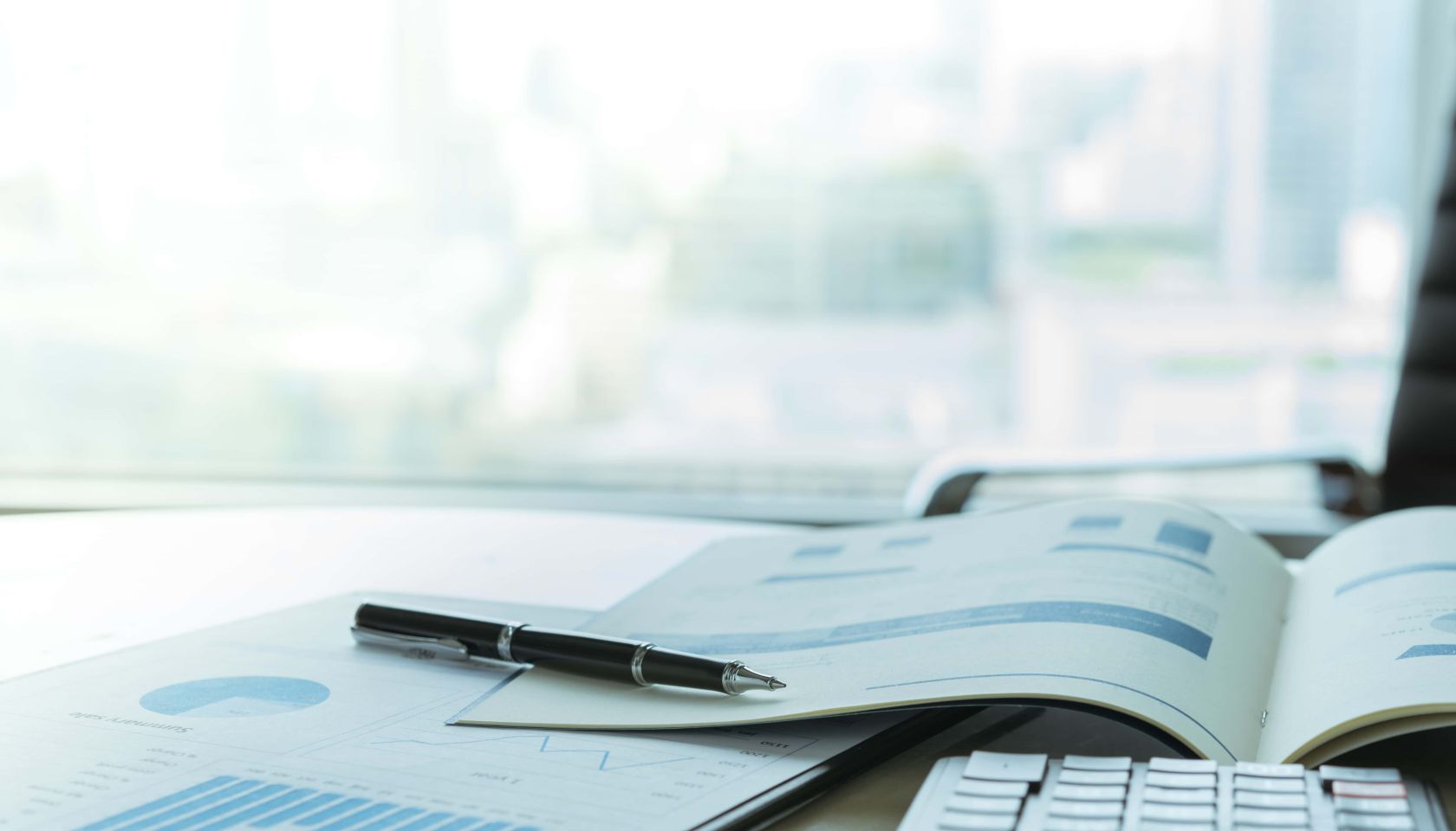 pen keyboard and financial documents laying on desk