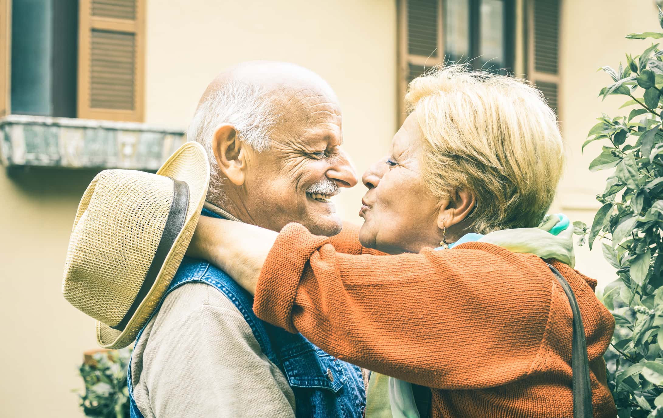 Happy senior retired couple having fun kissing outdoors at travel vacation - Love concept of joyful elderly and retirement lifes