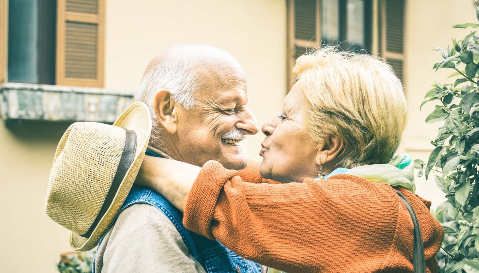 Happy senior retired couple having fun kissing outdoors at travel vacation - Love concept of joyful elderly and retirement lifes