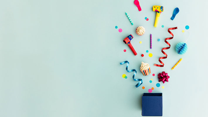 Objects for a birthday party coming out of dark blue box on a light blue background