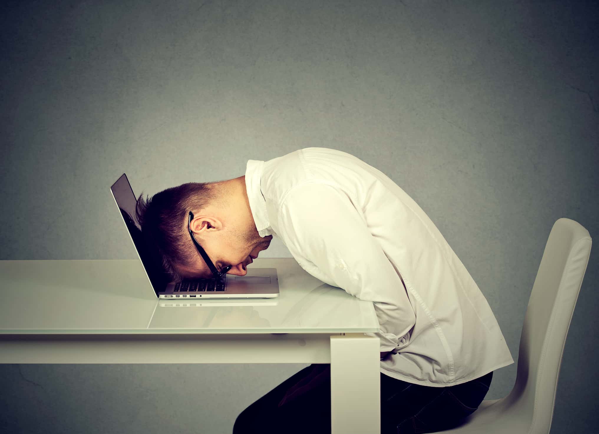 Desperate employee, stressed young man resting head on laptop keyboard