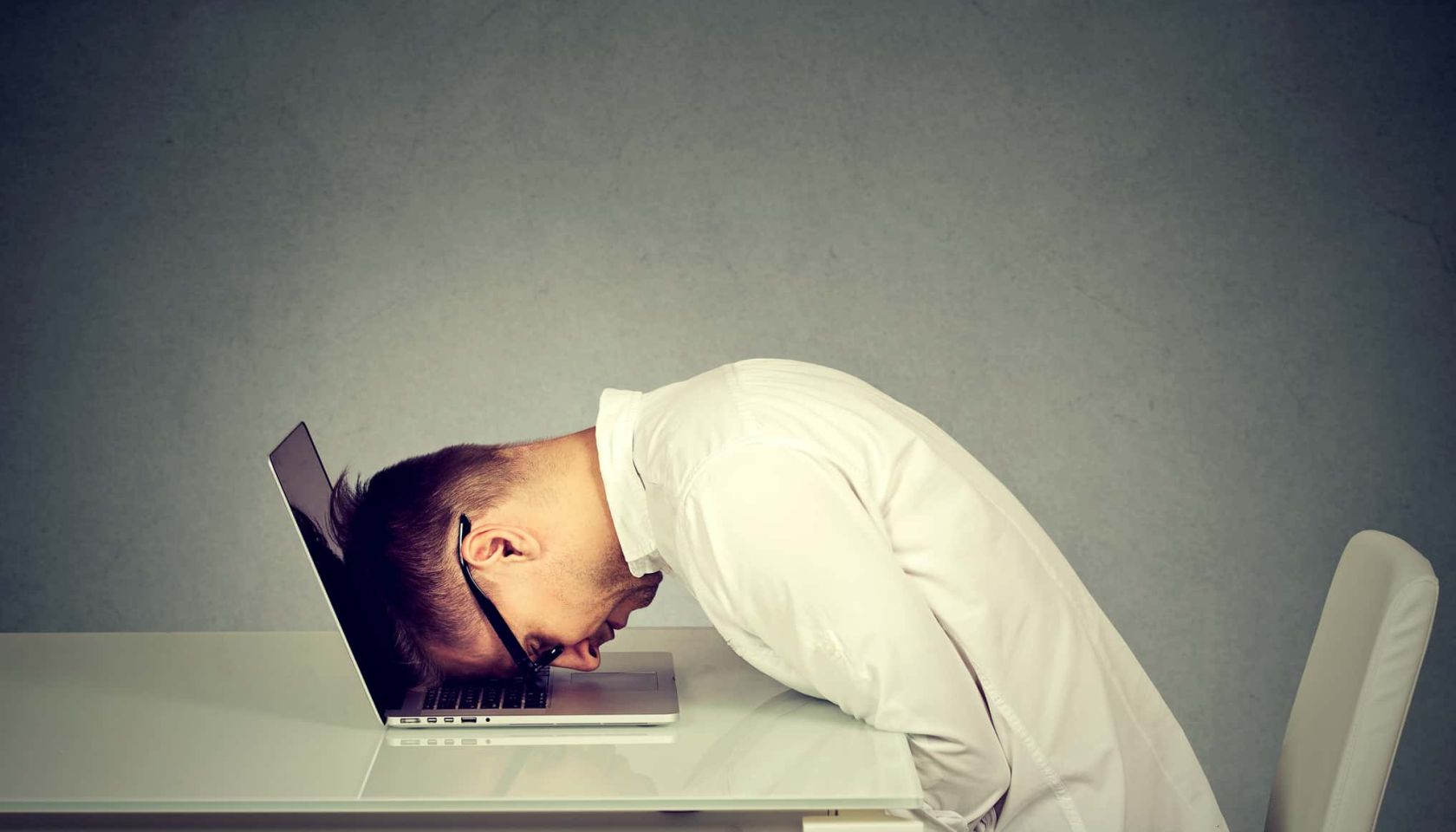 Desperate employee, stressed young man resting head on laptop keyboard