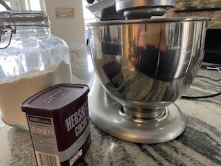 silver mixer and bowl with tin of cocoa and jar of flour