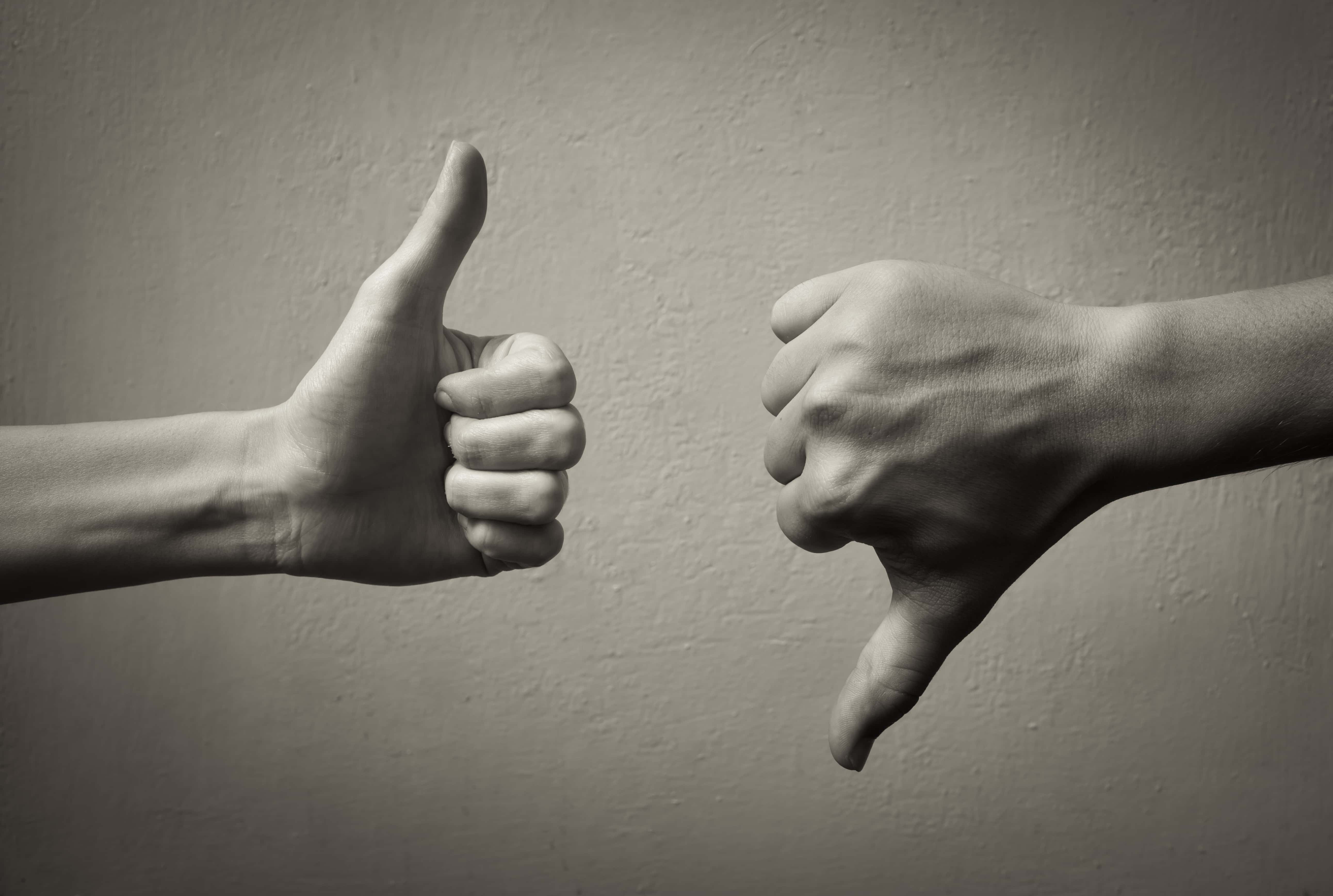 Photo of one hand with thumb up and an opposing hand with a thumb down