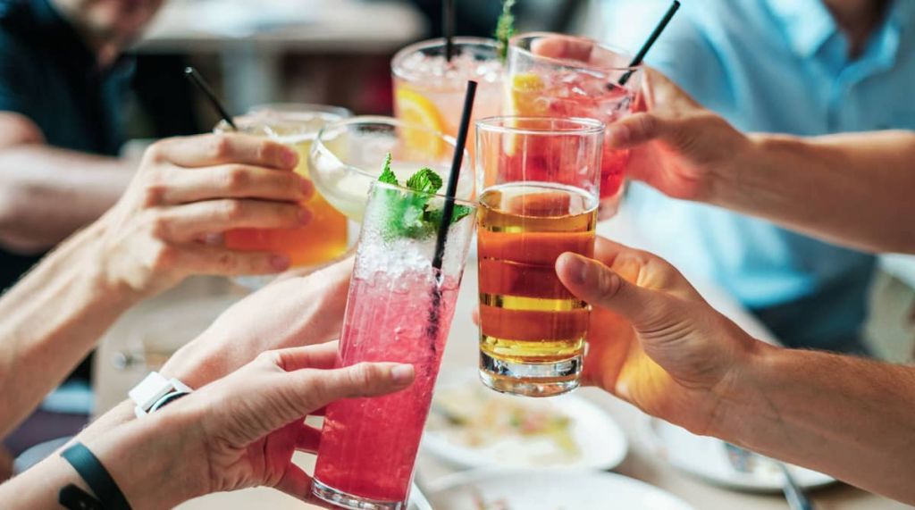 people holding and cheering their drinks