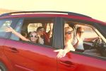 Happy smiling family with daughters in the car with sea background. Portrait of a smiling family with children at beach in the car. Holiday and travel concept
