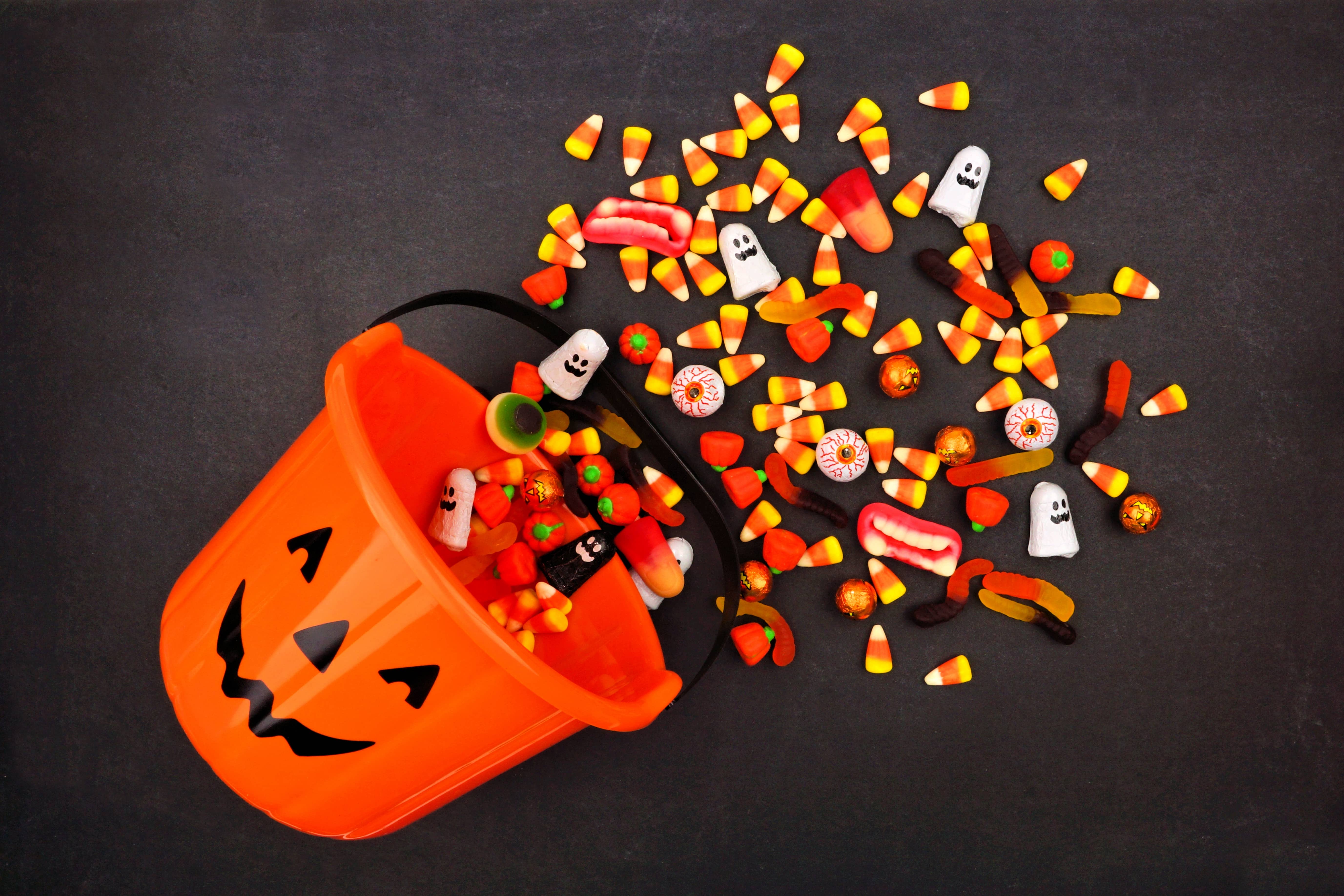 Lantern pail with spilling candy, above view on a dark background