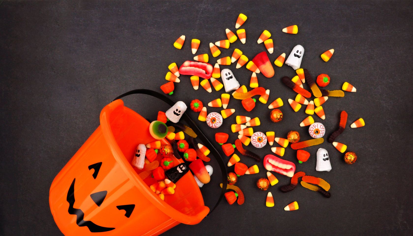 Lantern pail with spilling candy, above view on a dark background