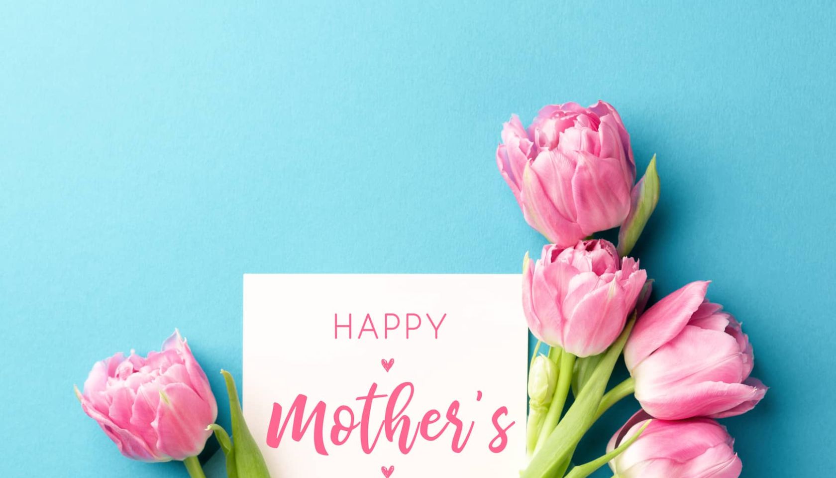 Bouquet of pink tulips in turquoise envelope on turquoise background. Happy Mother's Day greeting card. Flat lay, top view.