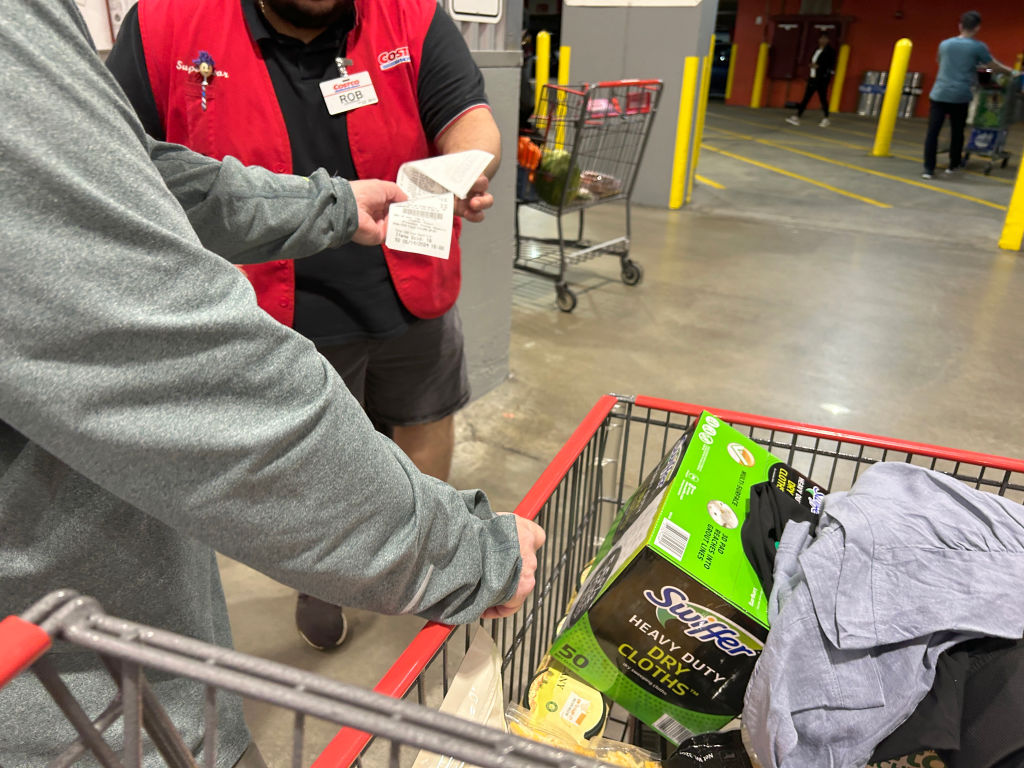 Customer handing receipt to door checker employee at exit, Costco megastore, Queens, New York
