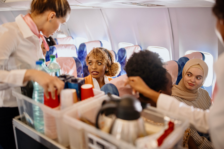Stewardesses serving food and drinks to customer on the airplane during flight