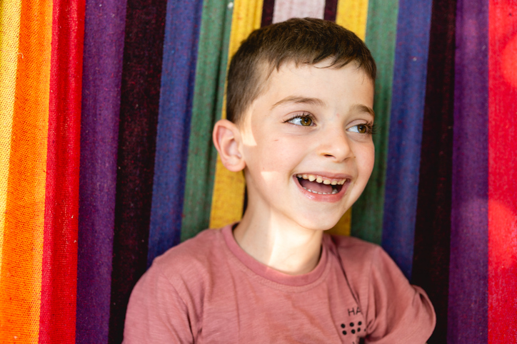 Smiling boy lying in a hammock enjoying and looking at camera
