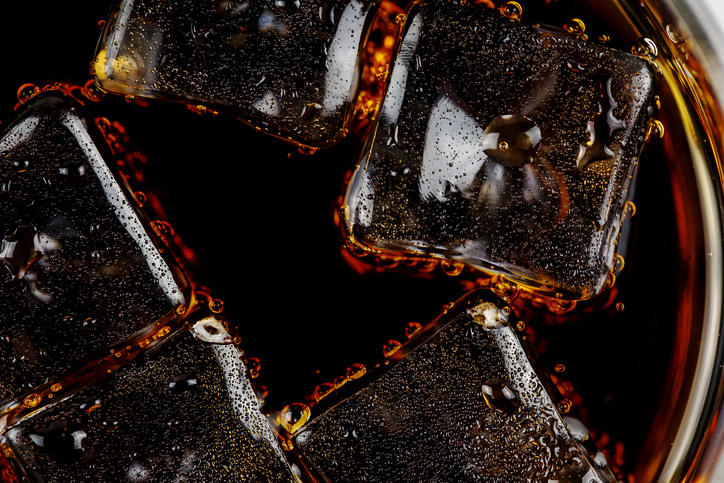 Carbonated drink with bubbles and ice on white background