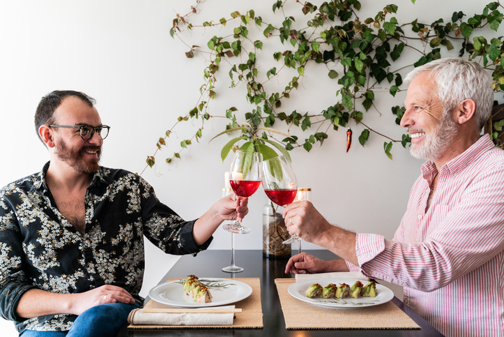 Gay couple toasting with wine glass during Japanese dinner at home