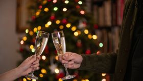 Couple chinking champagne glasses together in front of a christmas tree