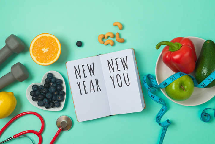 New Year resolutions concept. Healthy lifestyle and balanced diet vegetables, fruits, medical stethoscope, dumbbells and notebook on blue background