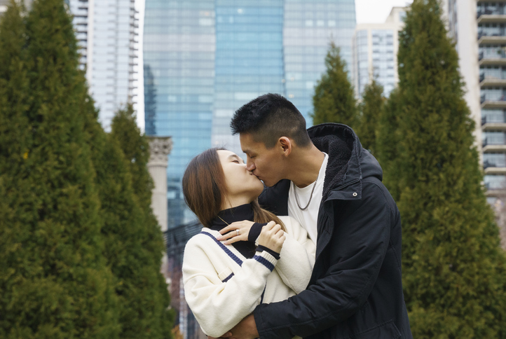 A young couple kisses after the young man proposes to his girlfriend in the park in Chicago, USA.
