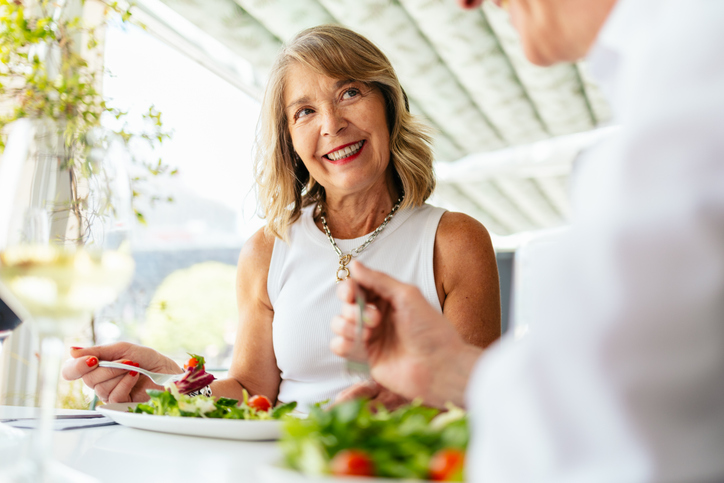 Senior woman enjoying healthy salad with friend in restaurant