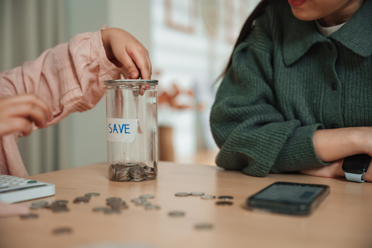 Mom teaching her daughter how to count coins and understand the value of saving