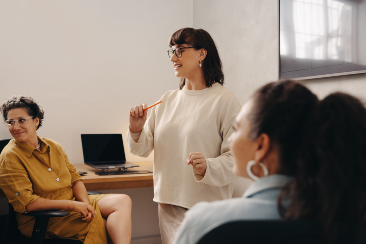 Team leader conducting discussion in a modern office setting with colleagues.