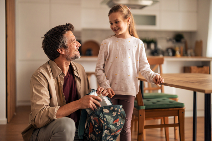 Father and Daughter Packing School Bag in the Kitchen