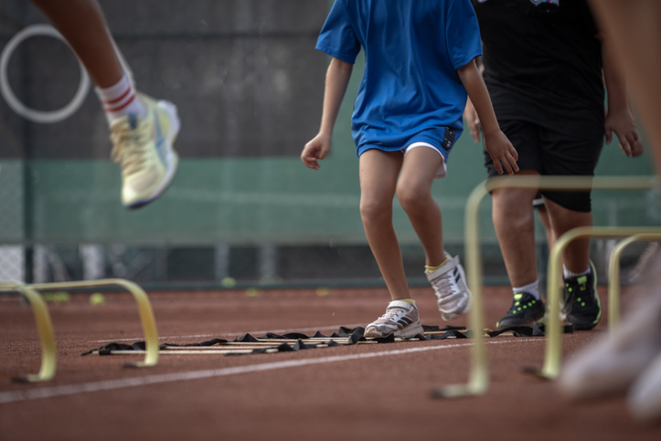 Beginner level kids focus on athletic training routine on the tennis court