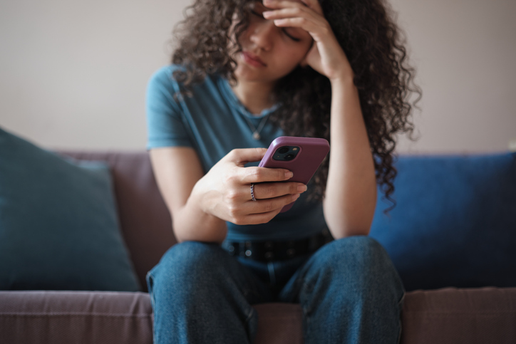 Close up of sad worried girl holding mobile phone touching forehead feeling anxious, depressed young woman with smartphone receiving bad news, upset teenager scrolling on social media. Gadget use and mental health