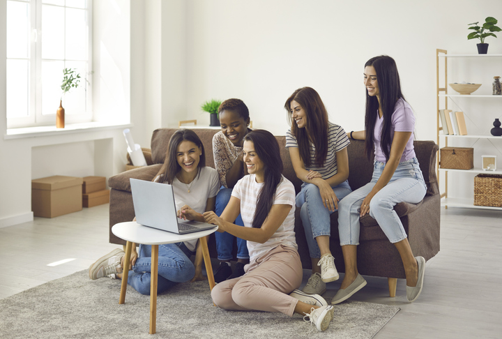 Smiling gen z diverse girls have fun using laptop