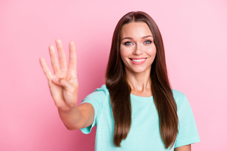 Photo portrait of positive happy girl showing four fingers counting isolated on pastel pink color background