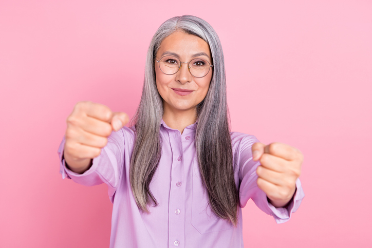 Portrait of attractive cheery focused gray-haired woman driving invisible car isolated over pink pastel color background