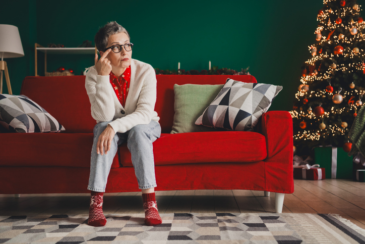 Charming elderly woman sitting in cozy and festive home interior with a decorated Christmas tree and holiday vibes