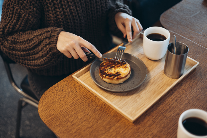 Woman eating quiche and drinking coffee at cafe break, close-up food.