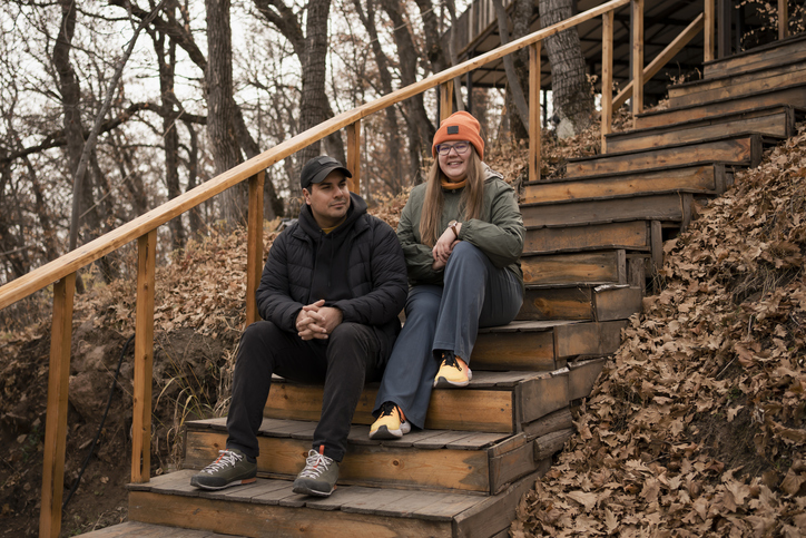 Happy young adult plus size couple in love sitting in autumn city park