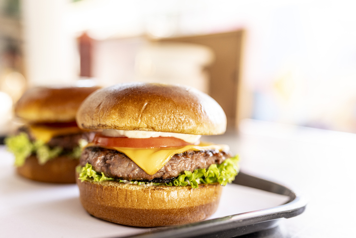 Readily cooked burgers on a tray at food truck counter.