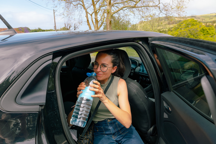 Woman drinking water from bottle during road trip