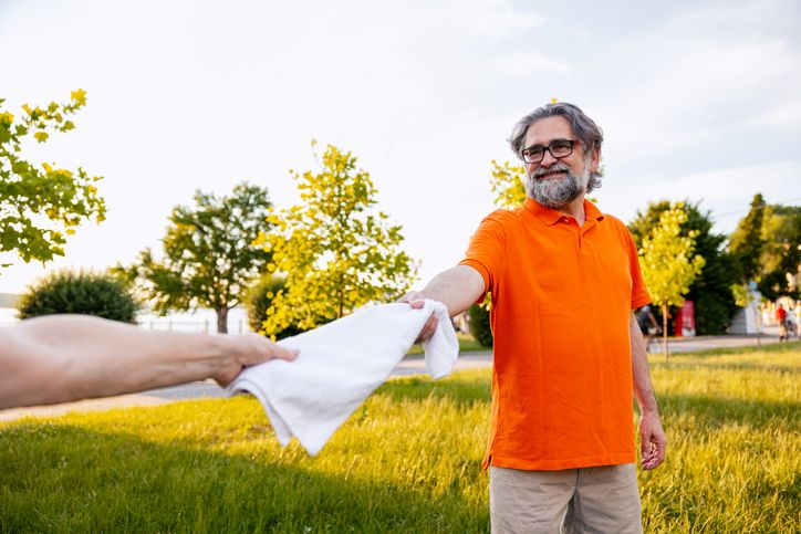 Senior adult man accepting refreshing towel outdoors