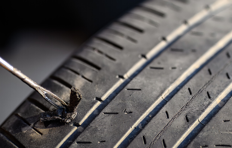 Close-Up Of Punctured Car Tire With Repair Plug Inserted In Tread Showing Damage And Wear