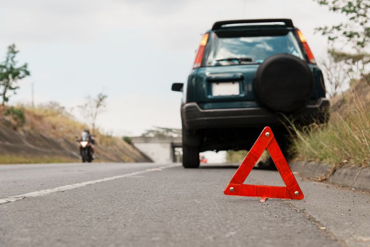Car breakdown with warning triangle on road shoulder